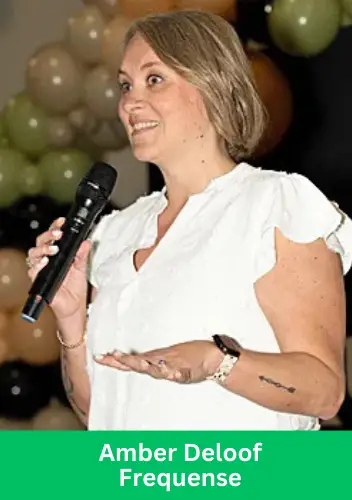 Amber Deloof speaking at a Frequense event, holding a microphone with a confident expression, surrounded by decorative balloons.