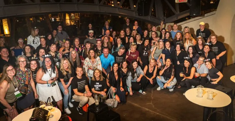 A large group of enthusiastic attendees at a Frequense event, celebrating and networking in a lively indoor setting