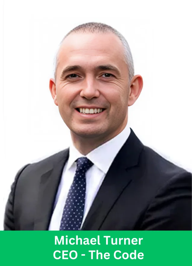 Michael Turner, CEO of The Code, smiling in a business suit on a white background