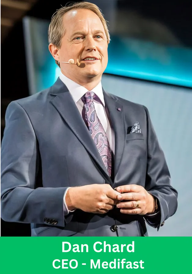 Dan Chard, CEO of Medifast, speaking on stage at a corporate event wearing a blue suit