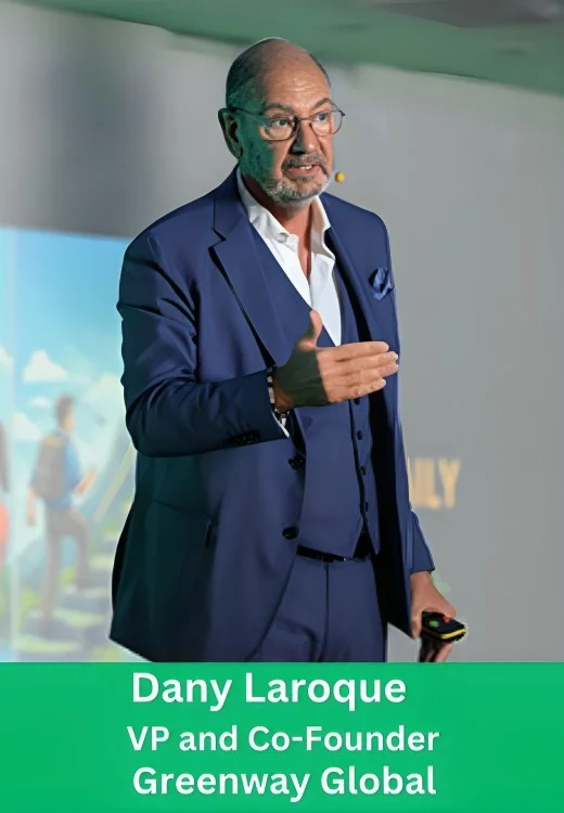 Dany Laroque, VP and Co-Founder of Greenway Global, speaking on stage at a corporate event in a blue three-piece suit.