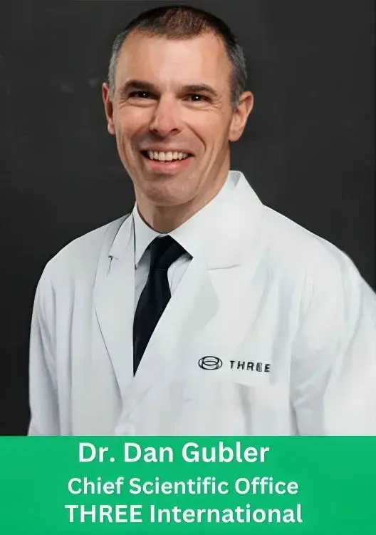 Dr. Dan Gubler, Chief Scientific Officer of THREE International, smiling in a white lab coat and black tie against a dark background.