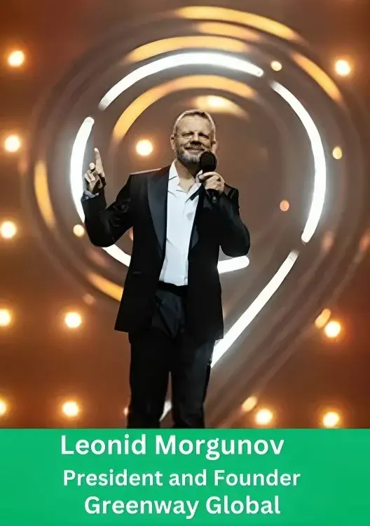 Leonid Morgunov, President and Founder of Greenway Global, speaking into a microphone on stage with a brightly lit, circular background graphic.