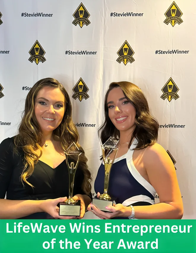 Two women from LifeWave proudly holding trophies after winning the Entrepreneur of the Year Award at The Stevie Awards. They are smiling in front of a #StevieWinner backdrop celebrating the victory