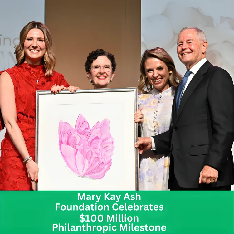 Mary Kay Ash Foundation team celebrating $100 million philanthropic milestone. Four people (women in red dress, glasses, patterned dress, and man in suit) smiling while holding a framed pink floral artwork at the event