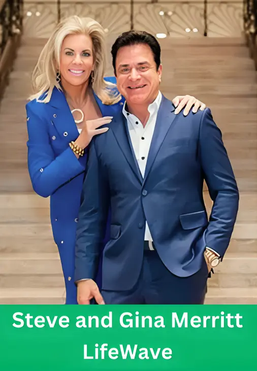 Steve and Gina Merritt smiling together on a staircase, with Gina wearing a bright blue suit and Steve wearing a matching blue blazer and white shirt.