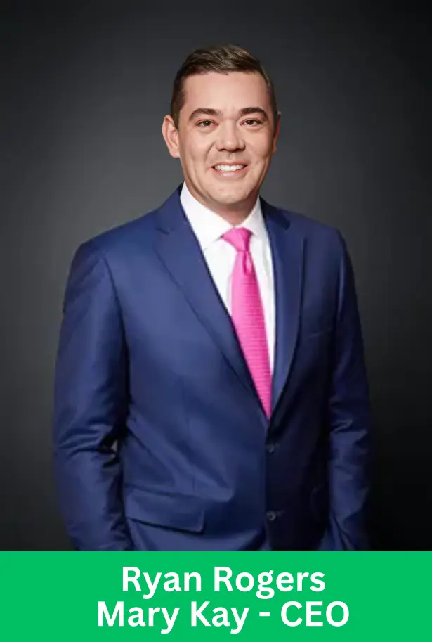 A professional portrait of Ryan Rogers, the CEO of Mary Kay, wearing a blue suit and a pink tie, against a dark gray background.